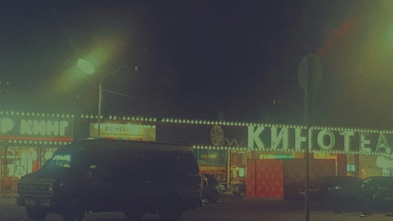 A dark van parked outside a cinema at night