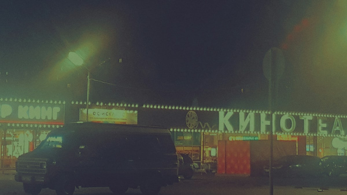 A dark van parked outside a cinema at night
